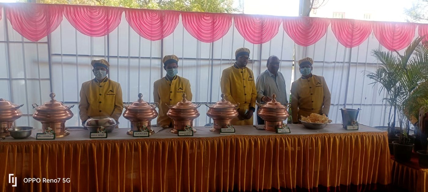 Service staff in uniform beside copper chafing dish counters